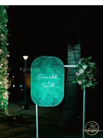 A personalized welcome sign with a tropical leaf motif for a modern, green-themed event.