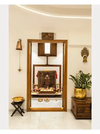 The Pooja room with its doors fully open, revealing the beautifully lit mandir inside. The design creates a seamless transition from the main living area to the sacred space.
