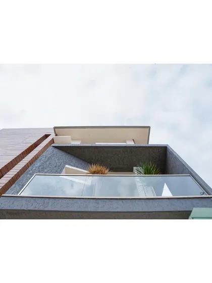 A close-up of the finished balcony with its glass railing and textured grey wall. This detail shot highlights the quality of finishes and the clean, minimalist lines that define the project.