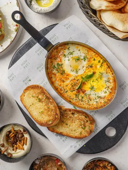 A sizzling pan of shakshuka with toasted bread. The tight framing and focus on the texture make this a powerful image for any cafe's all-day breakfast menu.