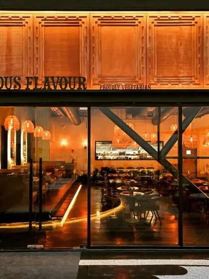 The facade is the first chapter of a brand's story. For the Indus Flavour restaurant, we designed a striking entrance that blends modern architectural lines with traditional motifs, featuring custom wood paneling and warm, inviting exterior lighting that draws patrons in.