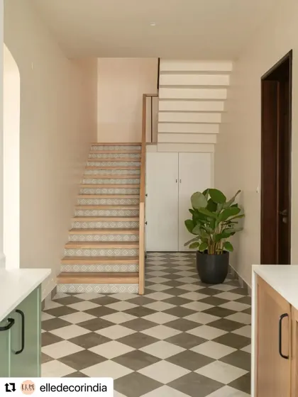 The staircase features checkerboard floor tiles that lead up to wood treads with patterned tile risers. This detail adds a touch of modern Indian sensibility to the home's design.