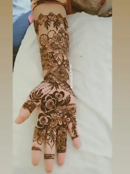 A lovely example of an Arabic floral design. The pattern starts with bold flowers on the palm and extends up the arm in a vine-like pattern, with simple bands on the fingers.