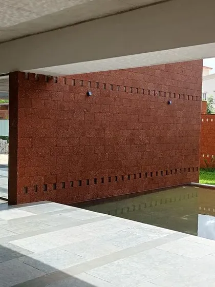 The entrance to a building at the Bagchi Karunashraya hospice, featuring a serene water body with a Buddha statue. The design uses these elements to foster a peaceful and contemplative atmosphere.
