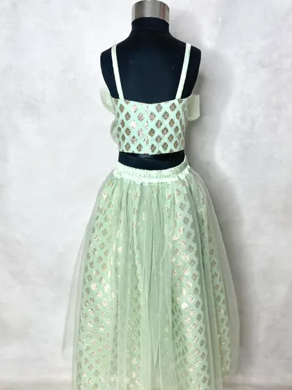 A closer look at the girl's soft mint lehenga, showing the delicate net overlay on the skirt and the simple, elegant crop top.