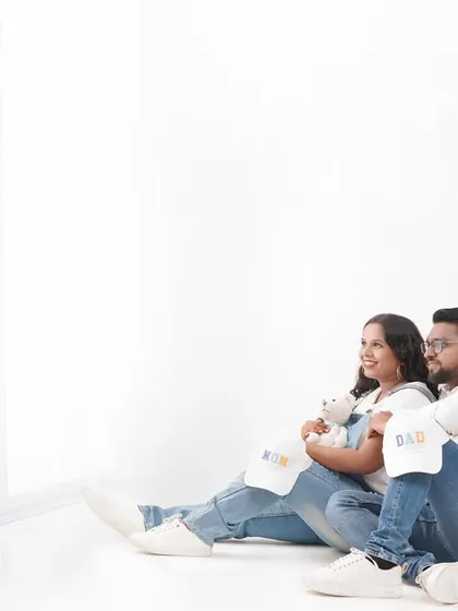 A relaxed moment from a casual maternity session. The couple is looking towards the future, with cute "Mom" and "Dad" hats adding a fun detail.
