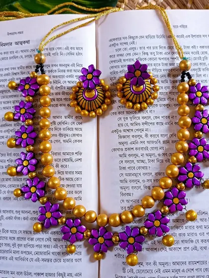 This floral choker features purple flowers on a string of golden beads, with matching jhumkas. It's an elegant choice for mehendi or sangeet functions.
