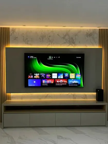 This TV unit design uses backlighting to create a floating effect. The combination of light wood, marble texture, and louvers adds warmth and sophistication.