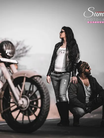 A creative, edgy portrait from a post-wedding shoot. The focus on the motorcycle wheel with the couple in the background adds a cinematic quality to their story.