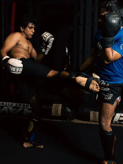 A dynamic shot of a fighter landing a kick during a sparring session.