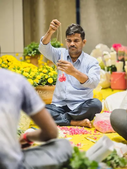 It’s the people behind the scenes that truly make an event. Here, one of our skilled artisans is carefully stringing fresh flowers, a craft that requires patience and precision.