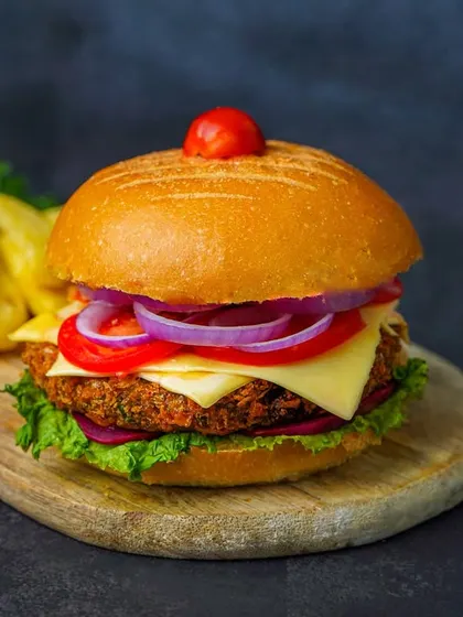 A straight-on shot of a tall, layered burger, making it look substantial and mouth-watering.