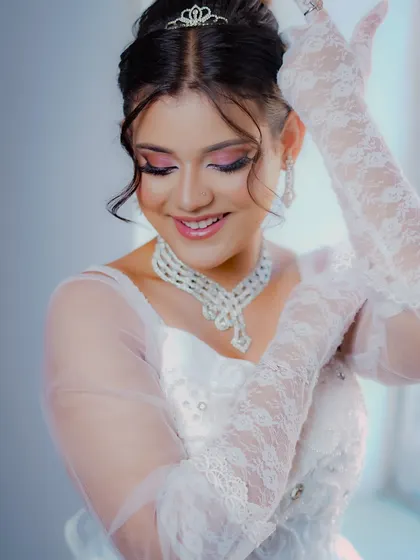 The lace gloves and gentle smile add to the timeless elegance of this classic bridal look.