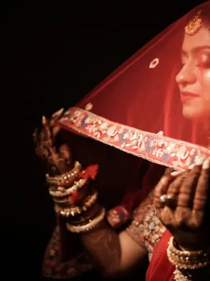 A close-up of the bride under her veil, her eyes closed in a moment of quiet contemplation. The lighting highlights the rich color of her attire.