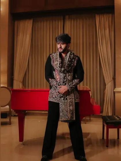 A client posing in a black Indo-Western outfit featuring a heavily embroidered stole. This look combines a simple base with a statement accessory for a unique and stylish effect.