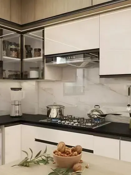 This L-shaped kitchen design features white glossy cabinets with black trim and glass-front upper units. The layout conveniently includes space for a washing machine.