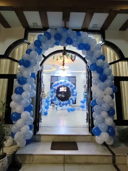 A grand entrance arch in blue and white balloons to welcome a baby boy home. This view shows how an entrance decoration can lead into the main party area inside.