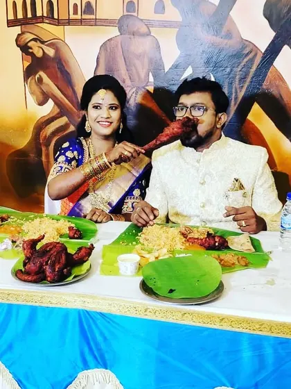 This couple enjoys their banana leaf meal against a backdrop of traditional art, perfectly blending culture and cuisine at their wedding reception.