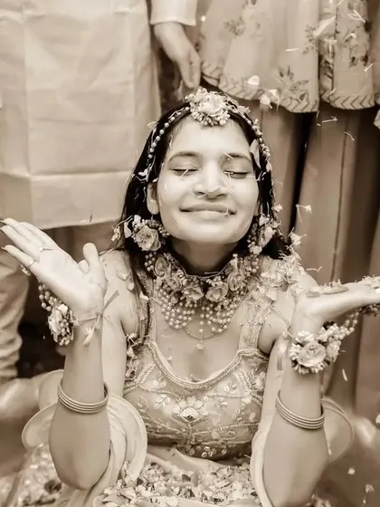 A moment of pure bliss during the Haldi. The bride, surrounded by her bridesmaids, throws her hands up as she's showered with flower petals.