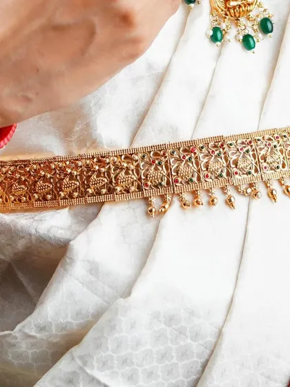 This image highlights the traditional gold waist belt, or 'vaddanam', showing its detailed pattern against the simple white saree. It's another example of how we capture key fashion elements for commercial clients.