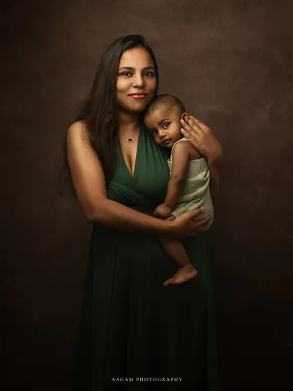 A beautiful fine art portrait of a mother and her baby. The deep green of her dress and the rich brown background create a warm and soulful image.