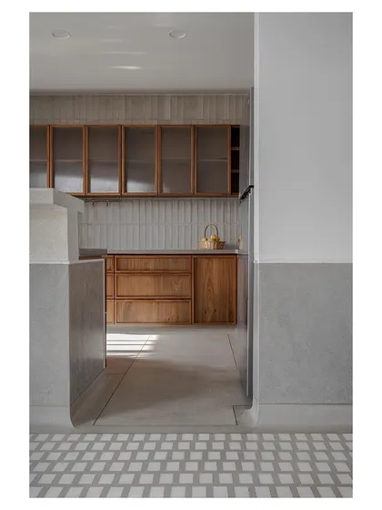 Sunlight streaming into the kitchen, catching the texture of the wooden cabinets and tiled backsplash.