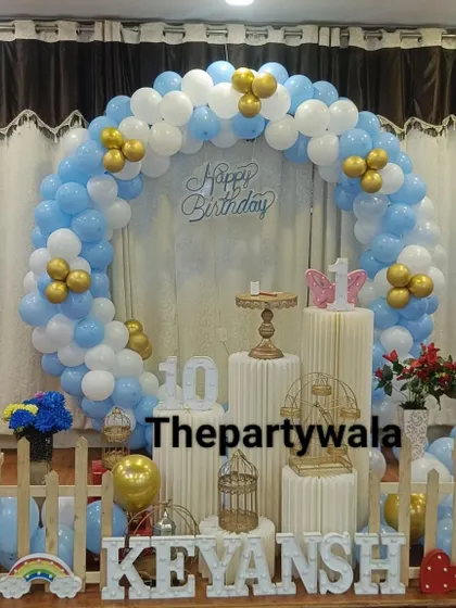 A blue, white, and gold balloon ring with a 'Happy Birthday' sign.