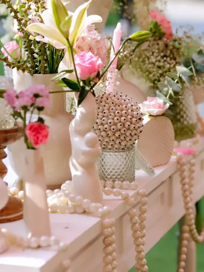 Details matter. A white console table is decorated with pearls, textured vases, and delicate pink and white flowers, adding a touch of vintage elegance.
