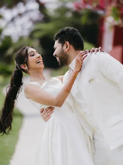A beautiful, candid moment of the groom dipping the bride as they laugh together, capturing pure joy and movement in a garden setting.