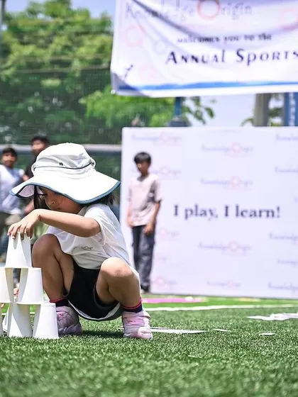 A child carefully stacks cups into a pyramid, an activity that requires focus and steady hands.