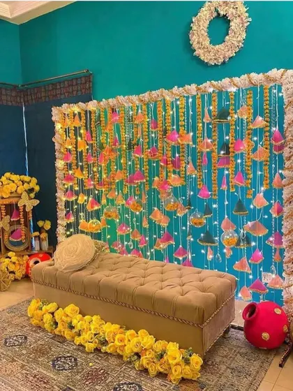 A beautiful Mehendi seating area with a backdrop of hanging gota patti tassels and fairy lights. The look is both traditional and whimsical.