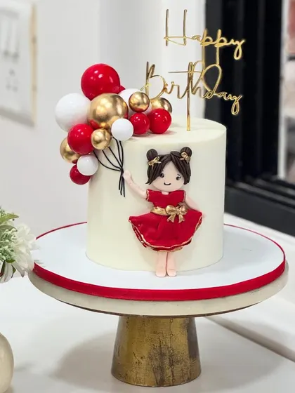 When handcrafted love meets festive colors! This adorable cake features a doll in a red dress holding balloons, perfect for a little one's magical birthday bash.