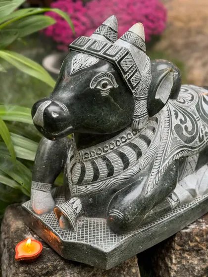 A seated Nandi statue, intricately detailed and carved from stone, represents the sacred mount of Lord Shiva and symbolizes devotion and loyalty.
