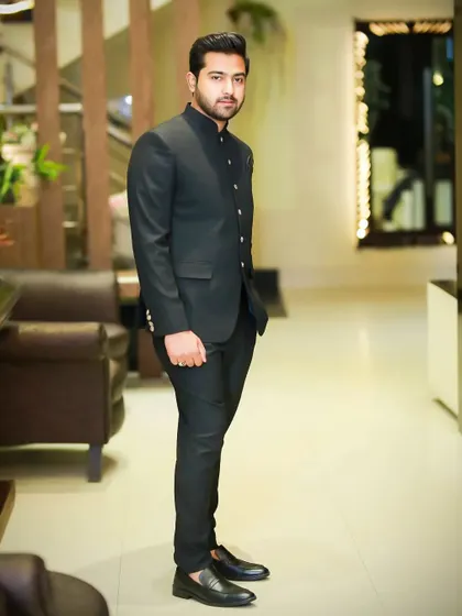 A classic black bandhgala suit, also known as a Jodhpuri suit. This is a timeless and elegant choice for a formal reception or engagement party.
