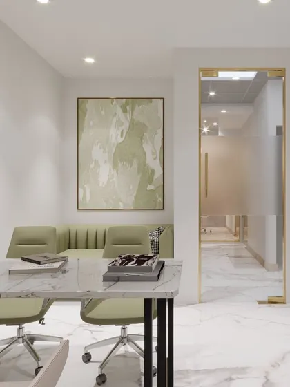 A minimalist cabin space featuring a clean white desk, a soft green sofa, and abstract art. The marble-patterned floor and gold-framed glass door add a touch of understated luxury.