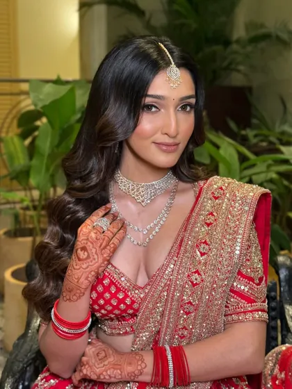A close-up showcasing the flawless makeup and intricate henna. The soft glam approach ensures her natural beauty is the focus, even with such a bold outfit.