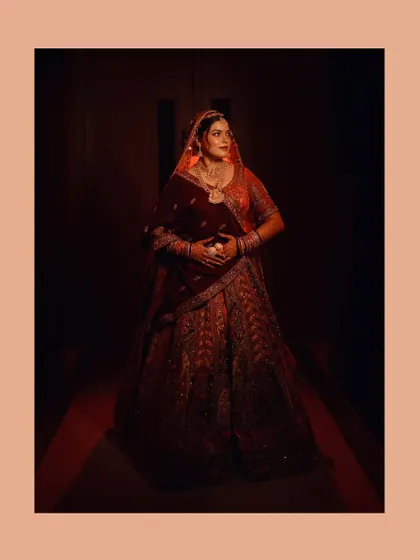 This full-length portrait showcases the bride's entire ensemble in a dramatic, low-light setting. The lighting is carefully placed to illuminate her and create a sense of grandeur, making her the absolute center of attention.