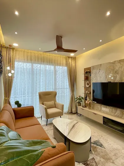 A wider view shows the elegant TV unit with a marble-patterned backdrop and fluted paneling. Every element, from the furniture to the lighting, is chosen to create a harmonious and stylish living space.