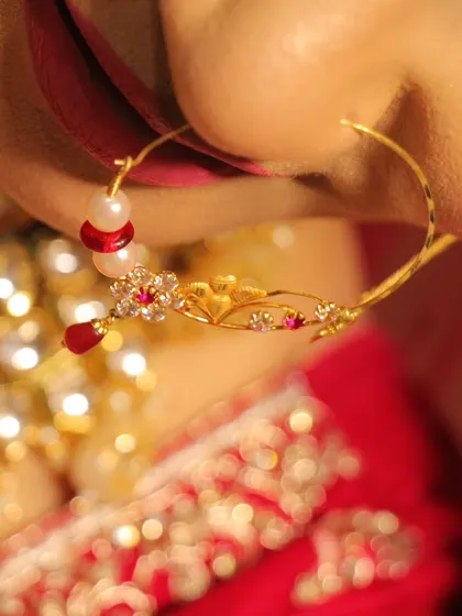 A macro shot of a bride's intricate gold nath (nose ring), highlighting the delicate craftsmanship of her wedding jewelry.