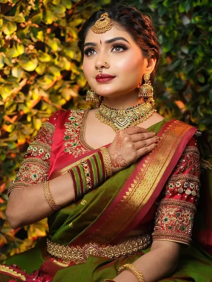 This shot highlights the rich colors of the olive green and red bridal saree. The drape is styled to beautifully display the embroidered sleeves and the heavy gold border of the saree.