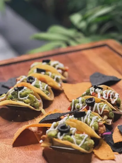 Another view of my guacamole-loaded mini tacos, presented on a rustic wooden board with assorted tortilla chips. The presentation is as important as the taste.