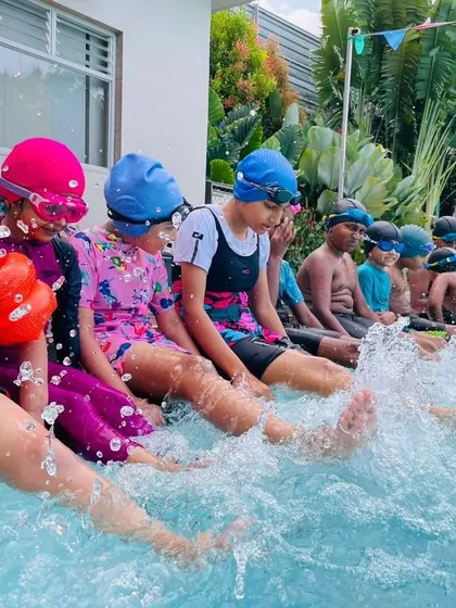 The simple joy of making a splash! Young swimmers in our Learn to Swim program have fun kicking at the edge of the pool, an essential drill for building leg strength and getting comfortable with the water.