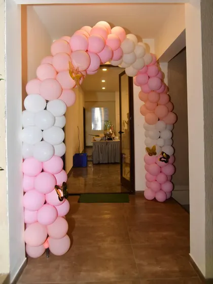 A simple yet charming butterfly-themed entrance arch made with pink and white balloons. Small butterfly cutouts are added to the arch for a subtle thematic touch.
