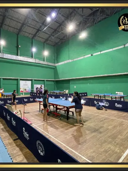 Players enjoying a game of table tennis in our spacious indoor hall. The facility is versatile, also marked for badminton, showcasing its multi-sport capability.