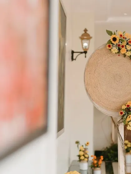 A decor detail featuring a woven jute disc adorned with a crescent of yellow flowers.