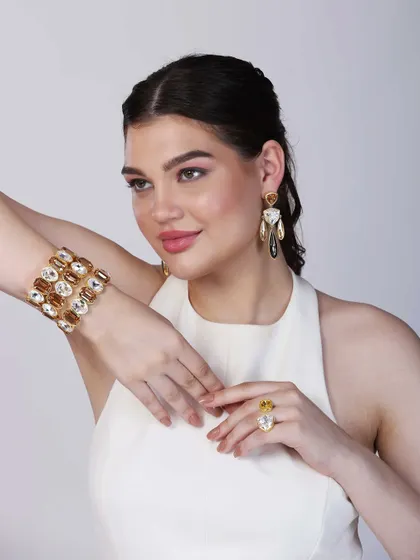 A dynamic pose that captures the shine and dimension of the stone-studded bracelet and dangling earrings, demonstrating how the pieces catch the light.
