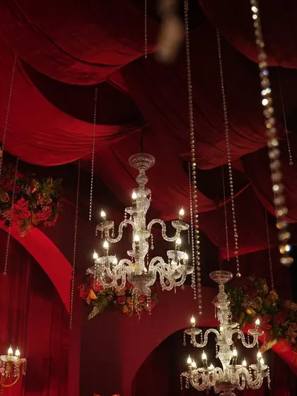 Another perspective of the hanging chandeliers against the deep red drapes, creating a dramatic and opulent atmosphere.