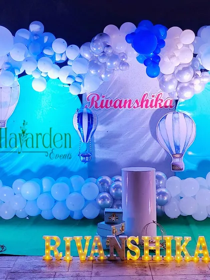 A full view of the hot air balloon themed stage, with marquee letters, a cloud-like balloon garland, and hot air balloon cutouts.