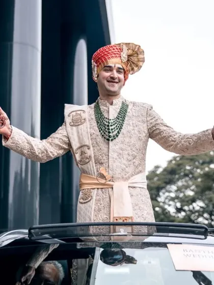 The groom making a grand and joyful entrance, standing in his wedding car. This shot captures his excitement and the energy of the baraat.