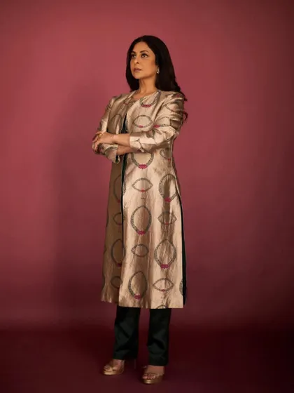The full look, pairing the long brocade jacket with simple dark trousers for a balanced and sophisticated ensemble.